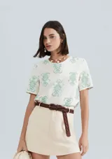 Blusa color salmón con estampado de flores blancas, de mangas cortas con volados y cuello redondo.