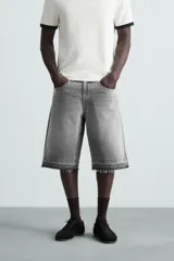 Bermuda de denim de algodón, color negro lavado, de corte ancho (baggy fit) y tiro medio. Presenta cinco bolsillos y bajo con acabado irregular deshilachado.