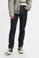 Jean de corte skinny, color azul oscuro, con tiro medio y cierre frontal con botón y cremallera. Presenta un diseño de cinco bolsillos clásico.