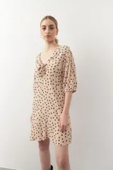 Vestido corto con estampado animal print en tonos beige y negro. Tiene mangas tres cuartos con elástico, cut-out en el frente y lazo.
