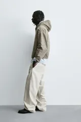 Cazadora boxy fit de algodón con estampado de cuadros en tonos beige y gris. Presenta cuello con capucha, cierre frontal de cremallera, mangas largas con puños elásticos y bolsillos frontales tipo canguro.