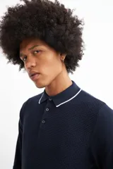 Sweater de punto color beige con cuello polo blanco y mangas largas.