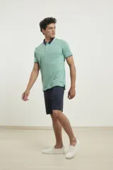 Chomba de piqué azul con cuello clásico, mangas cortas y corte recto. El cuello y los puños tienen detalles a contratono en azul marino y blanco.