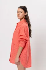 Camisa larga amplia color coral con patrón a cuadros, cuello camisero, cierre frontal con botones y grandes bolsillos en el pecho.