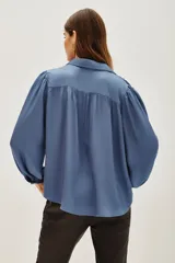 Camisa de viscosa en color marrón, con cuello clásico, cierre frontal de botones y mangas largas con puños abotonados.