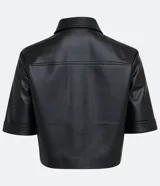 Camisa de manga corta confeccionada en cuero sintético color tostado, con cuello camisero, cierre frontal con botones en forma de corazón y dos bolsillos con solapa en el pecho.