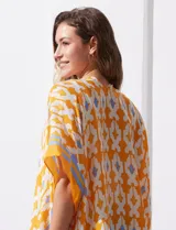 Kimono tejido con estampado abstracto en tonos azules, blancos y violetas. Tiene terminación de ruedo con borlas.