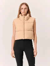 Chaleco puffer corto de diseño acolchado, con cuello alto y cierre frontal completo. Presenta un corte relajado y sin mangas.