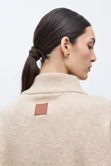 Sweater oversized color verde petróleo, con cuello alto y cierre frontal corto.