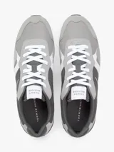 Zapatillas tipo runner de Tommy Hilfiger en tonos gris y gris oscuro, con detalles en blanco. Confeccionadas en una mezcla de cuero y textil, cuentan con pasadores blancos, suela de goma blanca y diseño lateral característico de la marca.