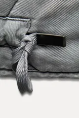 Chaleco gris acolchado con cuello alto, cierre frontal con cremallera metálica, bolsillos de plastrón en delantero y bajo ajustable con cordones.