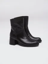 Botas de caña baja en cuero color marrón oscuro, con taco cuadrado y punta redondeada. Presentan un diseño tipo western con estribo desmontable que incluye una hebilla metálica decorativa.