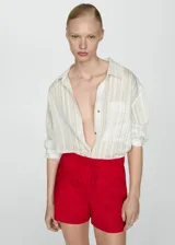 Short de tiro medio confeccionado en mezcla de lino y algodón. Presenta diseño corto, cierre lateral con cremallera invisible, trabillas en la cintura y lazo ajustable. Incluye dos bolsillos de ribete delanteros.