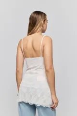 Vestido corto blanco confeccionado en encaje con silueta ajustada al cuerpo, escote recto y breteles finos.