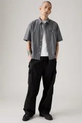 Pantalón cargo negro de corte holgado, con cintura elástica y cordón ajustable. Presenta bolsillos laterales y bolsillos cargo con solapa en los muslos.