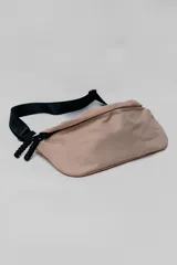 Bandolera de diseño minimalista en color beige, con correa ajustable negra y cierre frontal con tiradores de cordón.