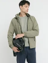 Campera de estilo deportivo en color verde oliva, con cierre frontal, cuello alto y puños elásticos.