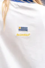 Remera tipo polo de manga larga con diseño de mangas raglán a rayas horizontales azules y blancas. El cuerpo de la prenda es blanco, con cuello polo y una pequeña estampa en el pecho. Confeccionada en tejido de algodón con spandex.