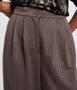 Pantalón wide leg de sastrería color gris con estampado de raya de tiza, tiro alto con cintura fija, pliegues delanteros y cierre frontal con botón y cremallera.