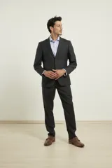 Traje de corte slim fit compuesto por saco de dos botones y pantalón de vestir a juego. Saco con solapas clásicas y bolsillos laterales, pantalón de corte recto y tiro medio.