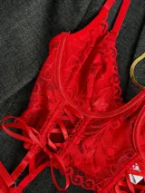 Conjunto de lencería rojo de encaje floral, compuesto por un corpiño tipo corset con aro y tirantes finos, una bombacha colaless regulable y ligas con cintas ajustables.