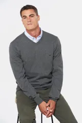 Suéter de tejido fino color azul marino, con cuello en V y manga larga. Presenta un pequeño logo bordado en el pecho.