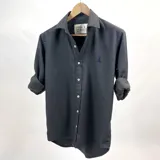 Camisa de vestir de algodón peletizado color azul grisáceo, de manga larga con puños abotonados y cuello clásico.