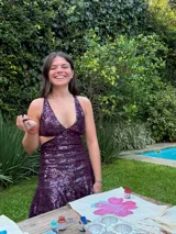 Vestido corto negro con estampado de plumas doradas, escote en V, breteles finos cruzados en la espalda, cut-outs laterales y volado en el ruedo.