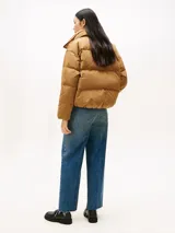 Campera acolchada de corte regular con cuello chimenea, cierre frontal a presión con botones dorados y hombros caídos. Presenta un diseño repelente al agua con relleno de plumas.