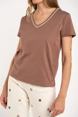 Remera de algodón peinado color blanco, con escote en V y detalles de lurex dorado en el borde del escote. De manga corta y corte ajustado.