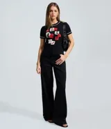 Remera negra de algodón con cuello redondo y mangas cortas con ribete blanco. Presenta un estampado frontal con motivos gráficos inspirados en la película El Diablo Viste a la Moda, incluyendo recortes tipo post-it, ilustraciones y texto.