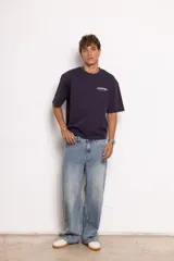 Camiseta azul marino de punto acanalado con corte boxy, cuello redondo y mangas cortas. Estampado del logo de la marca en el frente y la espalda. Bajo recto con terminación desflecada.