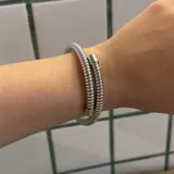 Pulsera plateada de metal con diseño de espiral.