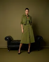 Falda midi verde con corte acampanado, bolsillos laterales con cierre y cintura alta.