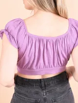 Blusa corta color amarillo, con escote redondo, mangas cortas abullonadas con volados y diseño cruzado en el frente.