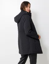 Campera capitoneada de corte largo con diseño de costuras multidireccionales, combinando un patrón de rombos en el cuerpo con capitoneado lineal en laterales y hombros. Cuenta con cierre frontal completo, cuello alto reforzado, capucha desmontable ajustable con cordones y bolsillos laterales con cierre invisible.