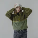 Buzo verde militar de sherpa con corte a la altura del pecho en tela lisa y cierre con cremallera amarilla.