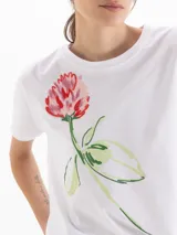 Remera blanca con estampado frontal de flor pintada al estilo acuarela, de manga corta y cuello redondo.