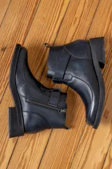 Bota corta de cuero color chocolate, con paneles frontales de gamuza en un tono más oscuro. Presenta una tira decorativa sobre el empeine, cierre lateral y suela de goma negra con plataforma baja.