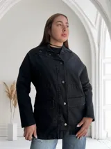 Sobrecamisa negra de jean con cuello camisero, cierre frontal con botones metálicos, bolsillos de parche en el pecho y corte recto.