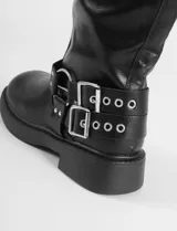 Botas de caña media color marrón, confeccionadas en cuero sintético, con suela de caucho y diseño decorado con múltiples hebillas metálicas ajustables.