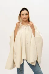 Poncho tejido en telar en 100% lana merino color crudo, con capucha y cordones de ajuste.