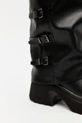 Bota alta marrón de diseño slouchy con plataforma track y múltiples hebillas metálicas decorativas en la parte lateral exterior de la caña.