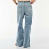 Jeans de mezclilla en tono azul medio con tiro alto y corte flare, con aberturas laterales en el dobladillo inferior.