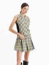 Vestido corto sin mangas con estampado de cuadros escoceses en tonos verde, amarillo y azul. Presenta un diseño ajustado en el torso con paneles laterales negros, falda tableada con vuelo y cinturón integrado con hebilla en la cintura.