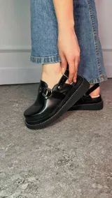 Zuecos cerrados tipo sandalias de plataforma, confeccionados en cuero con efecto craquelado en tono azul, con tiras texturizadas, argollas metálicas decorativas y tira trasera con hebilla regulable.