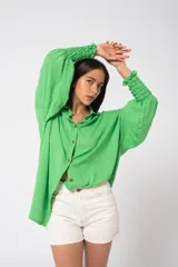 Camisa oversize color fucsia, de lino, con cuello camisero, cierre frontal con botones y mangas largas abullonadas con puños elásticos.