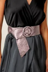 Cinturón ancho de cuero con acabado metalizado en tono visón, con hebilla redonda forrada en el mismo material.