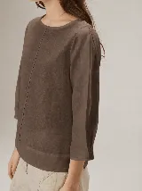 Blusa de algodón color marrón, con escote redondo, mangas tres cuartos con volumen sutil y costuras verticales decorativas en el frente.