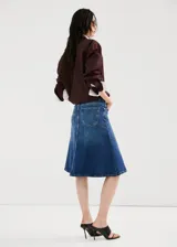 Falda midi evasé de denim estilo vaquero, con tiro medio, trabillas, diseño de cinco bolsillos y cierre frontal con botón y cremallera.